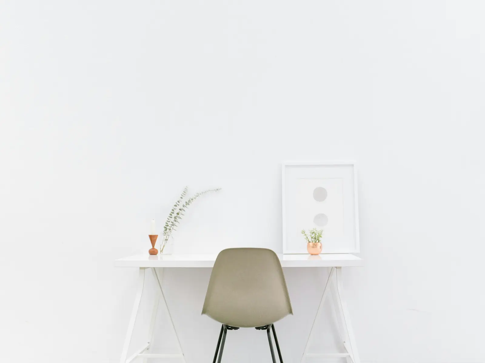 White desk and a single chair against a white wall
