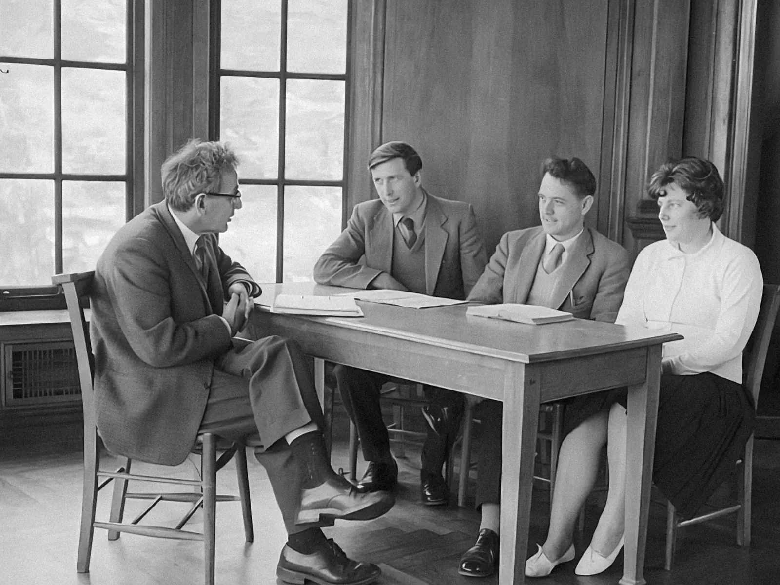 Black and white photo of a team meeting around a wooden table